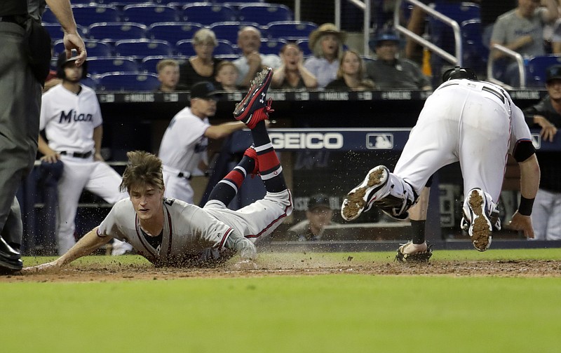 Atlanta Braves pinch-runner Max Fried, left, scores the go-ahead run past Miami Marlins catcher Chad Wallach on a double hit by Ender Inciarte during the 10th inning of Sunday's game in Miami. The Braves won 3-1.