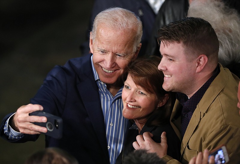 Former Vice President Joe Biden, a 2020 Democratic presidential candidate, hugs supporters during a photo-op with audience members during a recent rally in Des Moines, Iowa.