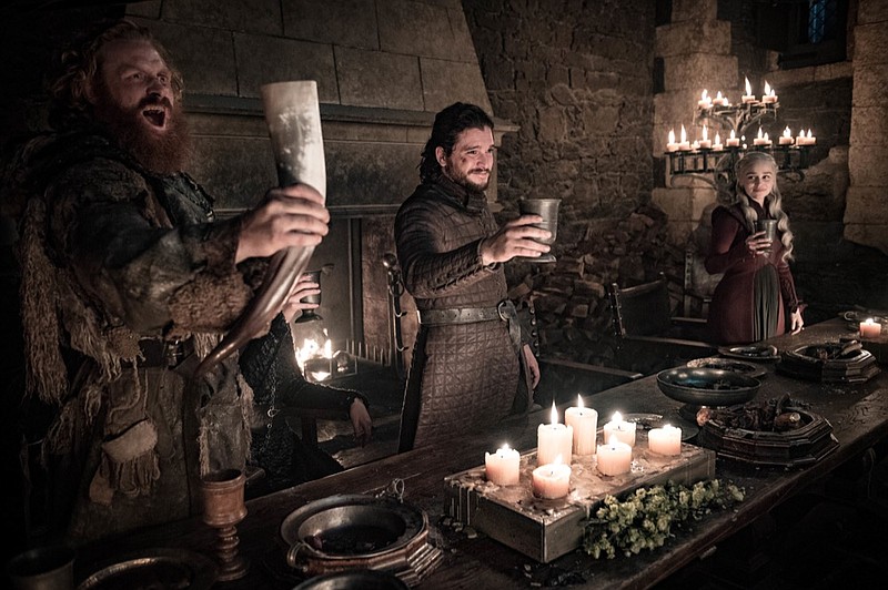 This image released by HBO shows Kristofer Hivju, from left, Kit Harington and Emilia Clarke in a scene from "Game of Thrones." fans got a taste of the modern world when eagle-eyed viewers spotted a takeout coffee cup on the table during a celebration in which the actors drank from goblets and horns. The characters Daenerys and Jon did not react to the out of place cup in Sunday s episode. Many viewers complained the show should have caught the gaffe, which turned into an enduring meme on Monday.(Helen Sloan/HBO via AP)


