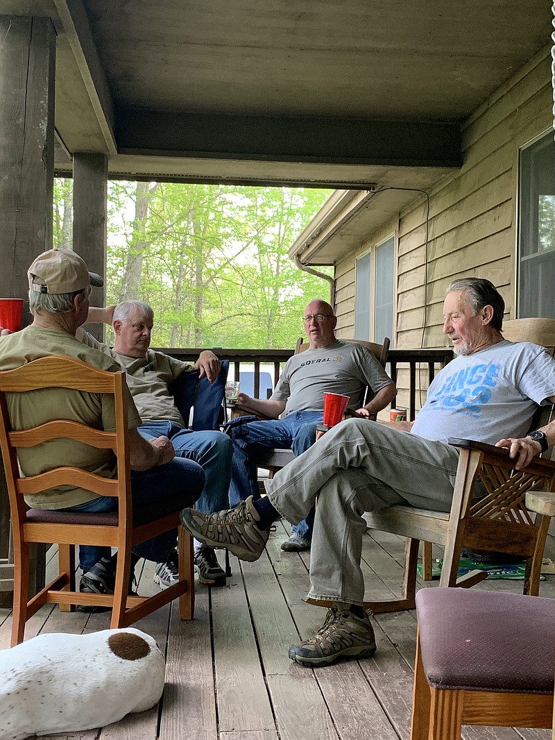 Outdoors columnist Larry Case, second from right, and his turkey hunting buddies participate in the daily back porch session that precedes supper each evening in camp during their annual spring gathering.