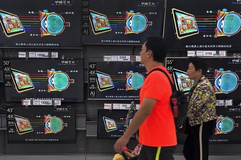 Chinese shopper walk by shelves displaying Chinese-made flatscreen TV's at Walmart in Beijing, Thursday, May 9, 2019. Chinese exporters of all sorts of products, from power adapters and computers to vacuum cleaners, are anxiously hoping trade talks in Washington this week will yield a deal that might stave off higher U.S. tariffs on imports from China. (AP Photo/Andy Wong)

