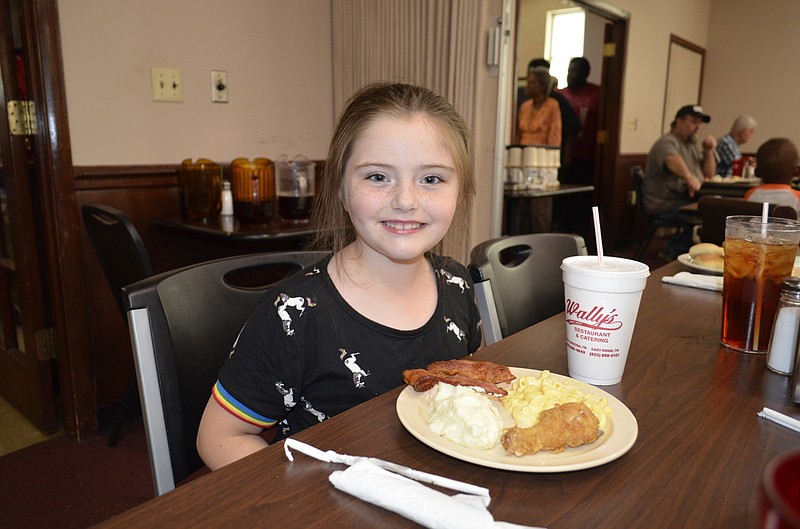 Rylan Howell enjoys a plate of fried chicken, macaroni and cheese, mashed potatoes and bacon during the 30th anniversary celebration at Wally's Restaurant in East Ridge.