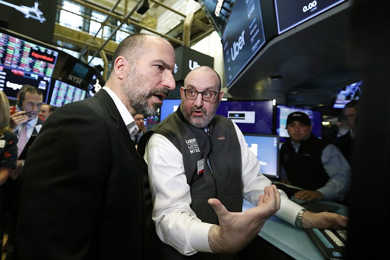 Uber CEO Dara Khosrowshahi, left, talks with specialist Peter Giacchi before his stock begins trading at the New York Stock Exchange, as his company makes its initial public offering, Friday, May 10, 2019. (AP Photo/Richard Drew)