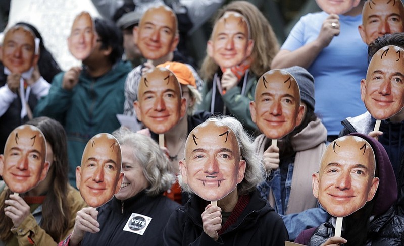 FILE - In this Oct. 31, 2018, file photo, demonstrators hold images of Amazon CEO Jeff Bezos near their faces during a Halloween-themed protest at Amazon headquarters over the company's facial recognition system, "Rekognition," in Seattle. San Francisco is on track to become the first U.S. city to ban the use of facial recognition by police and other city agencies as the technology creeps increasingly into daily life. Studies have shown error rates in facial-analysis systems built by Amazon, IBM and Microsoft were far higher for darker-skinned women than lighter-skinned men. (AP Photo/Elaine Thompson, File)

