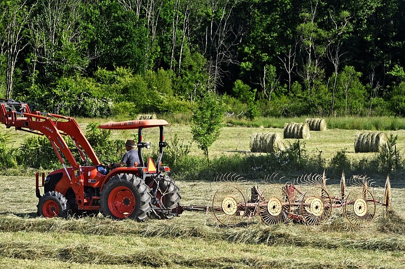 Staff Photo by Robin Rudd/
A farmer pulls a set of wheel rakes behind his tractor as a hay field a long U.S. Highway 27 is readied for baling in the Bakewell Community in North Hamilton County on May 7, 2019.  According to the University of Tennessee Institute of Agriculture the state ranked 10th national in the production of hay in 2015.  