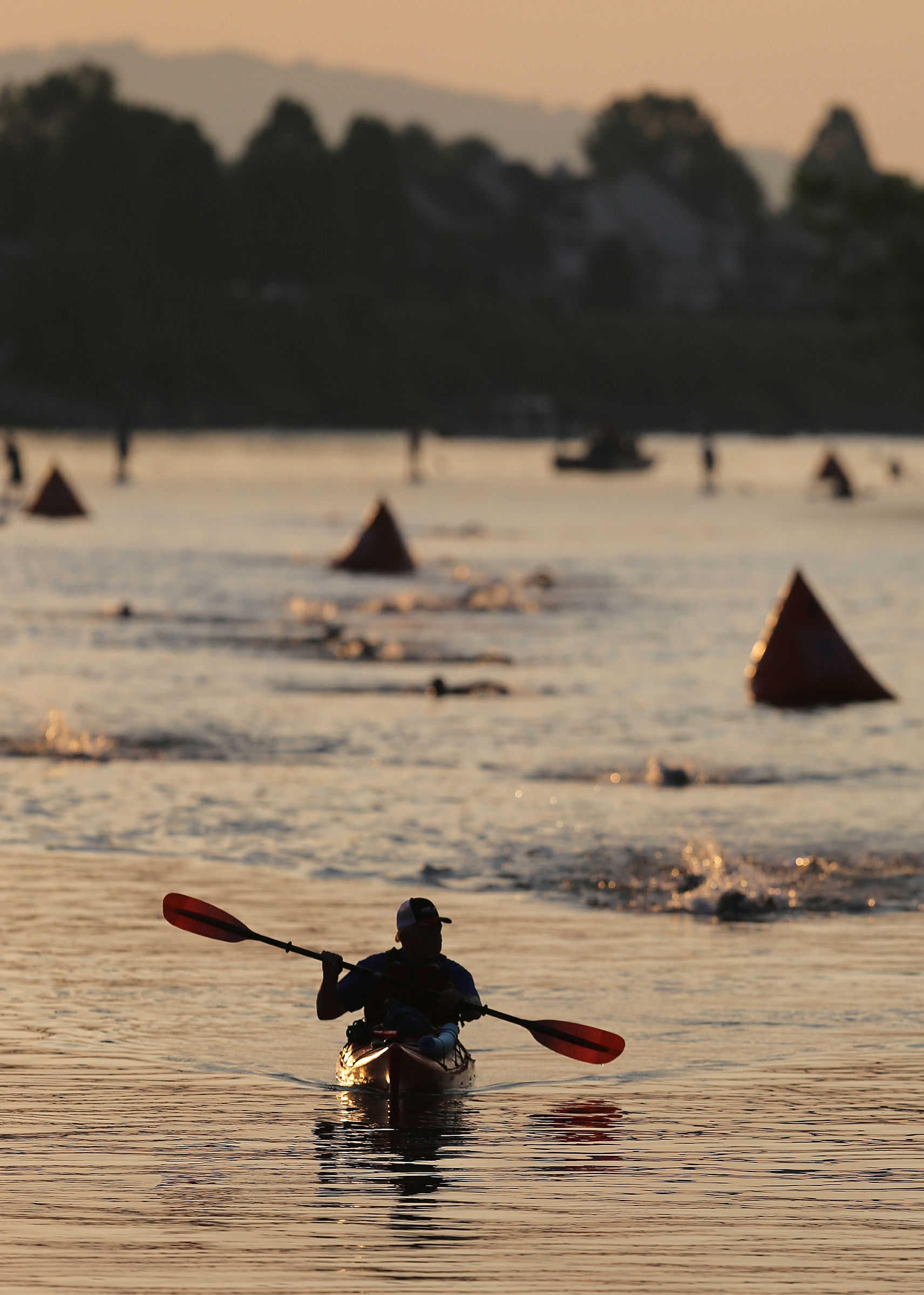 A volunteer leads the first group of swimmers to the takeout area during Ironman 70.3 Chattanooga Sunday, May 20, 2018 in Chattanooga, Tenn.