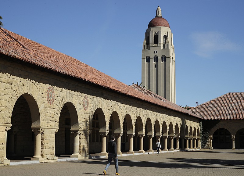 FILE- In this March 14, 2019, file photo, people walk on the Stanford University campus beneath Hoover Tower in Stanford, Calif. The amount of free money you receive for college may decrease after your freshman year. To hang on to scholarships and grants, and avoid paying more for your education than you expected, understand the terms of your financial aid offer, contact your school’s financial aid office if your income changes and plan ahead for tuition increases.(AP Photo/Ben Margot, File)