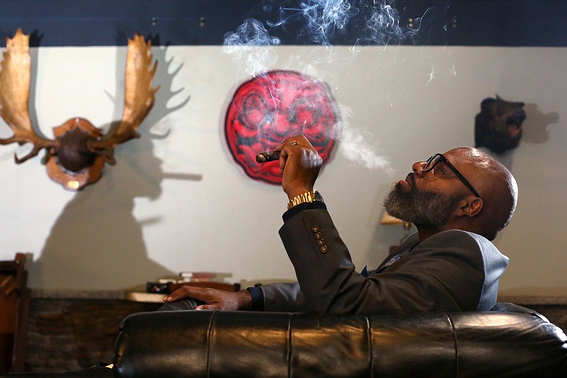 Mark Franklin's shadow is cast on the wall as Chris Abernathy Sr. smokes a cigar.