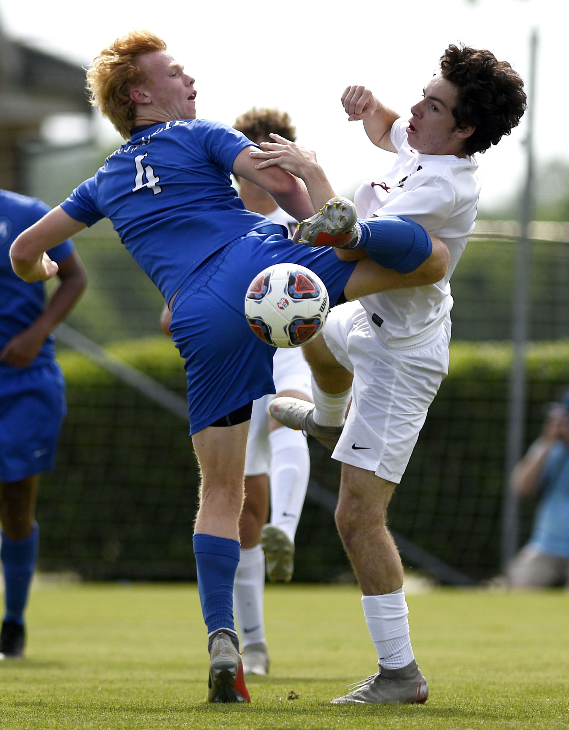 McCallie's Noah Tremain (4) strains to kick the ball as he collides with a MBA player. McCallie faced Montgomery Bell Academy for the TSSAA Division II Class AA state soccer championship at the Richard Siegel complex on May 23, 2019.