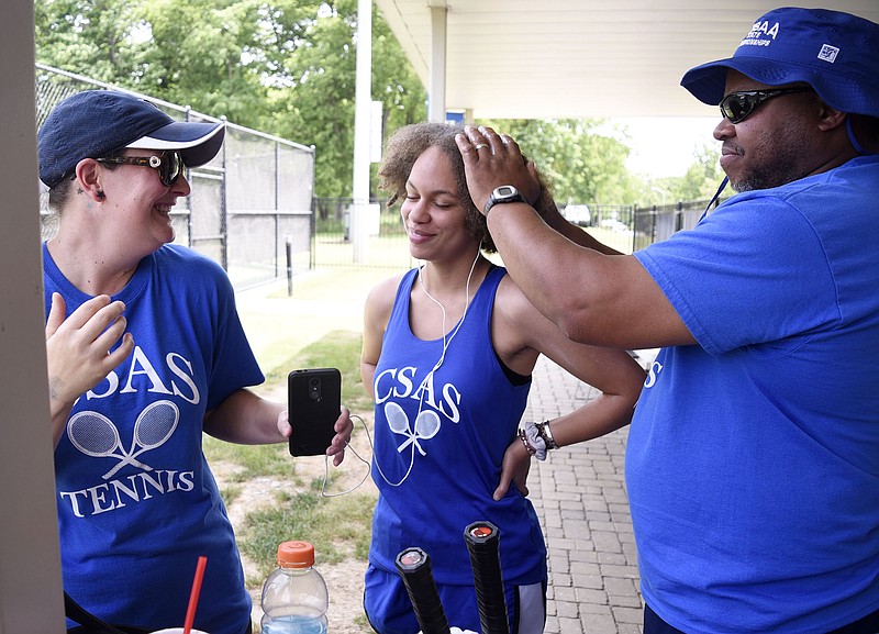 Arts & Sciences tennis player Sunshine Finnell has sunblock applied by her father while her mom looks on during a break in play at the Division I Small Class girls' singles state tournament Thursday at the Adams Tennis Complex in Murfreesboro.