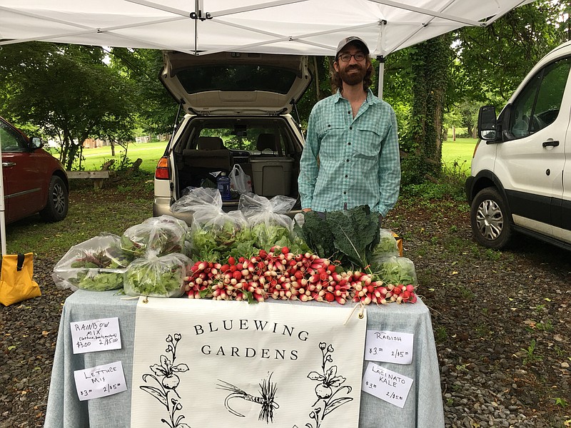 Corey Callihan of Bluewing Gardens displays produce from the farm on the market's first day in its new location at McCoy Farm & Gardens. / Contributed photo by Teresa Garland