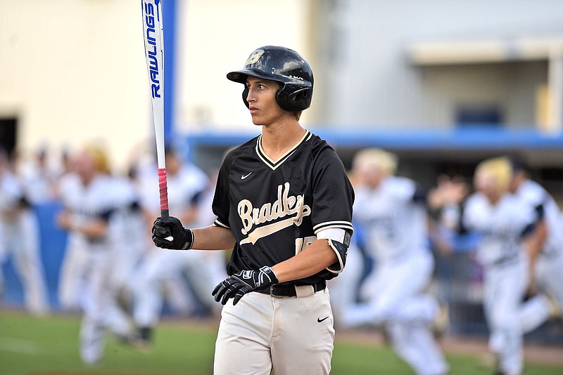 Bradley Central's Logan Weeks twirls his bat after making the final out of the TSSAA Class AAA state final Friday night at MTSU. In the background, the Farragut Admirals charge the field to celebrate their state championship after winning 7-3.