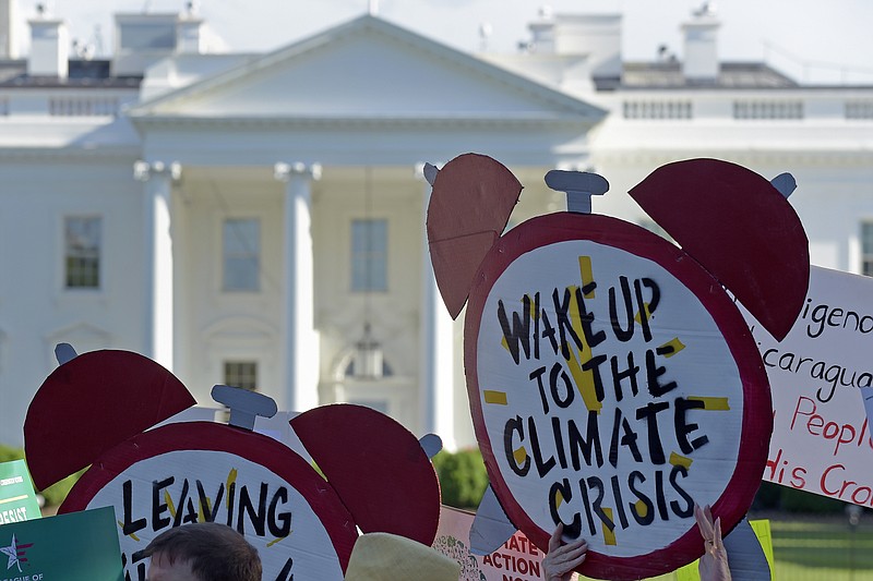 FILE- In this June 1, 2017 file photo, protesters gather outside the White House in Washington to protest President Donald Trump's decision to withdraw the Unites States from the Paris climate change accord. (AP Photo/Susan Walsh)