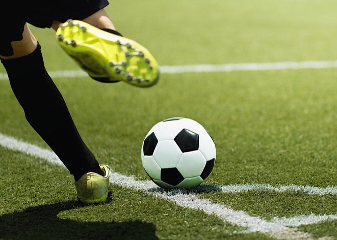 Foot of a soccer player and ball on the football field, kicking a corner kick soccer tile / Getty Images