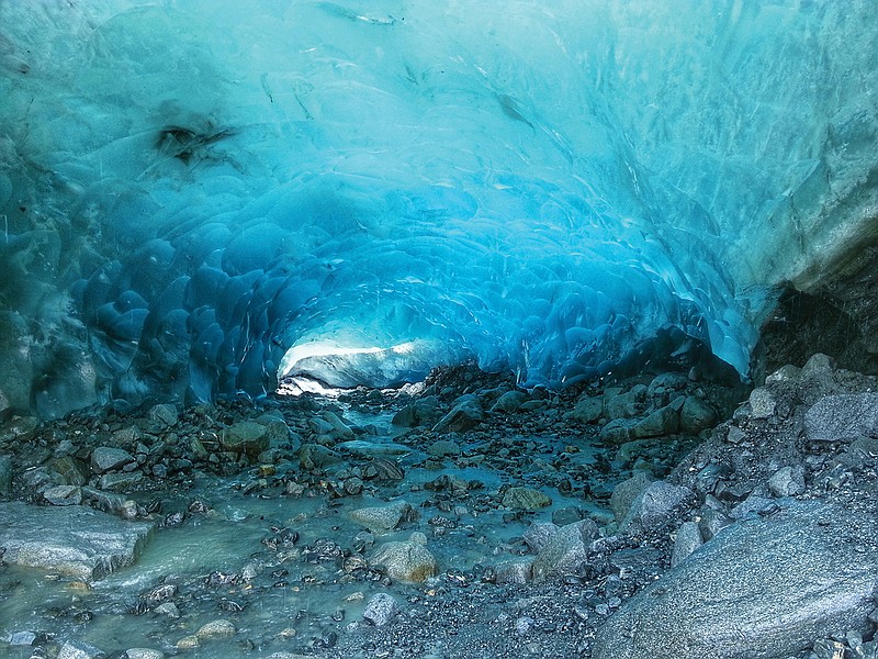 A stream flows into the ice cave below the glacier, Alaska.