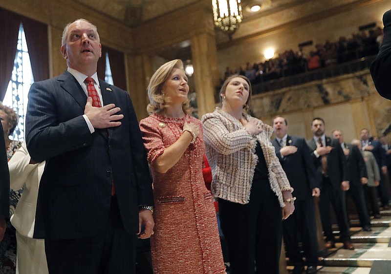 In this Monday, April 8, 2019, file photo, Louisiana Gov. John Bel Edwards holds his hand to his heart with his wife, Donna Edwards, and their daughter Sarah Ellen Edwards, right, during the pledge of allegiance at the opening of the annual state legislative session in Baton Rouge, La.