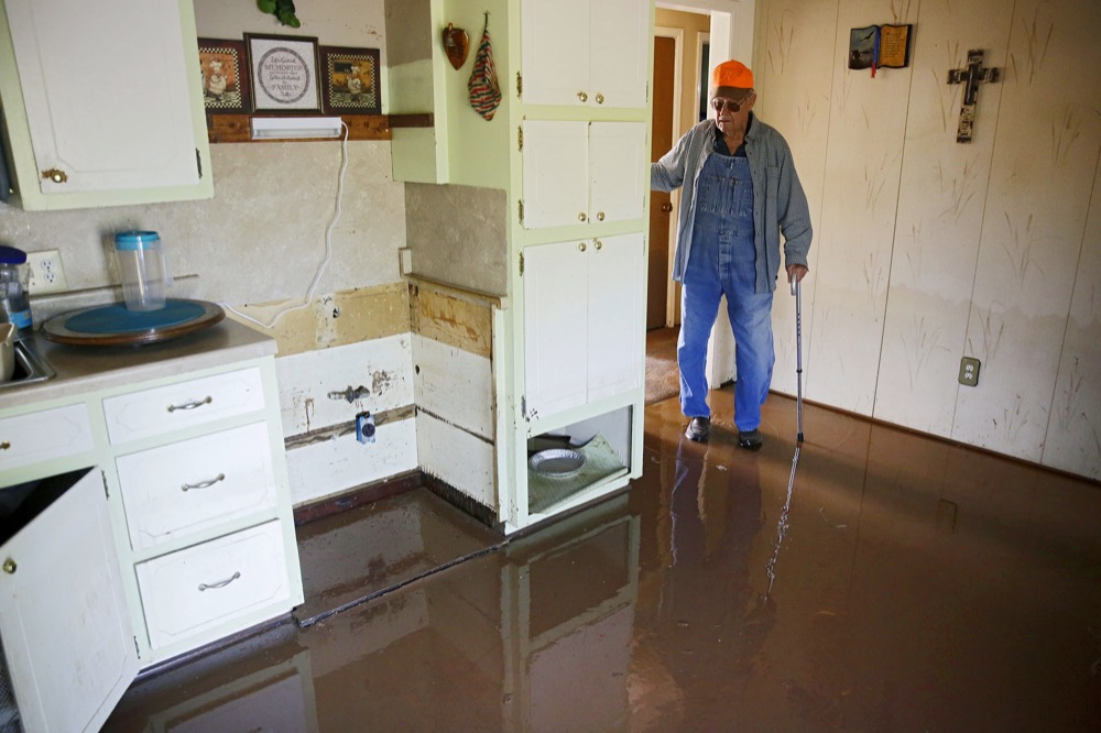 In this Thursday, May 30, 2019 photo, Eugene Bowers looks at the kitchen in his flooded home in the Town and Country neighborhood west of Sand Springs, Okla. (Mike Simons/Tulsa World via AP)