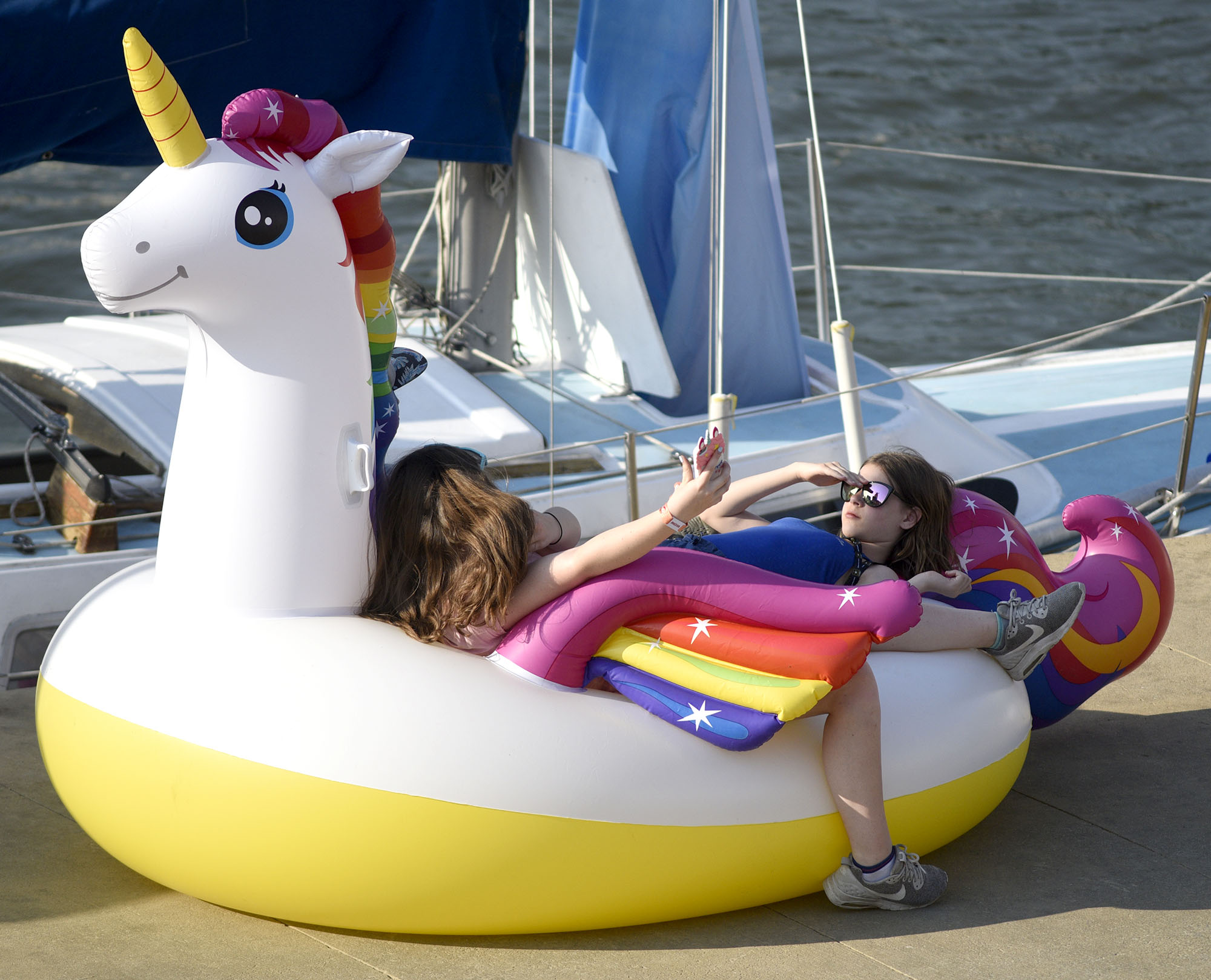 Three young people use a inflateable unicorn for a couch before the acts begin at Riverbend.