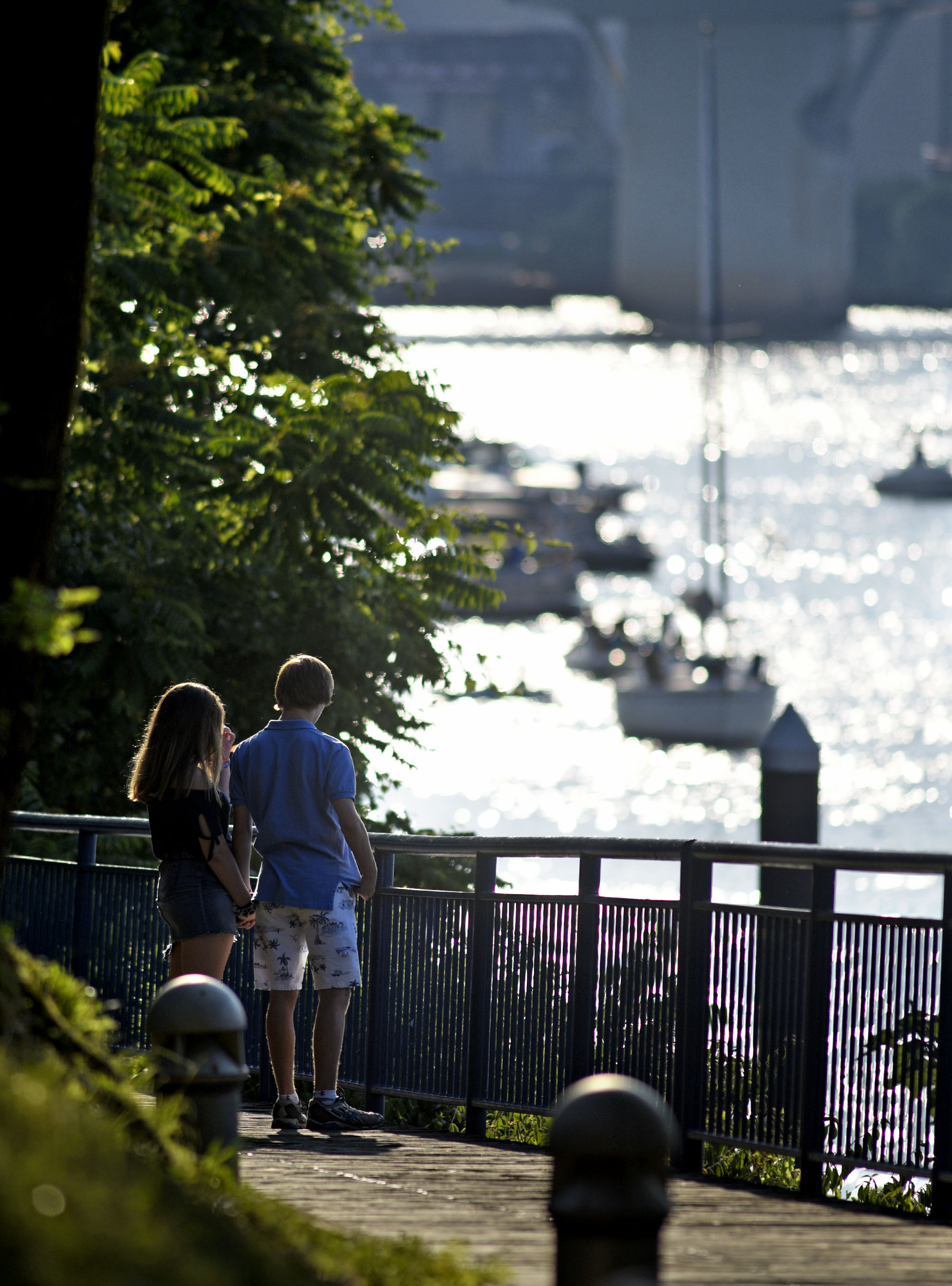 A couple strolls along the Riverwalk as the Tennessee River glistens in the background.