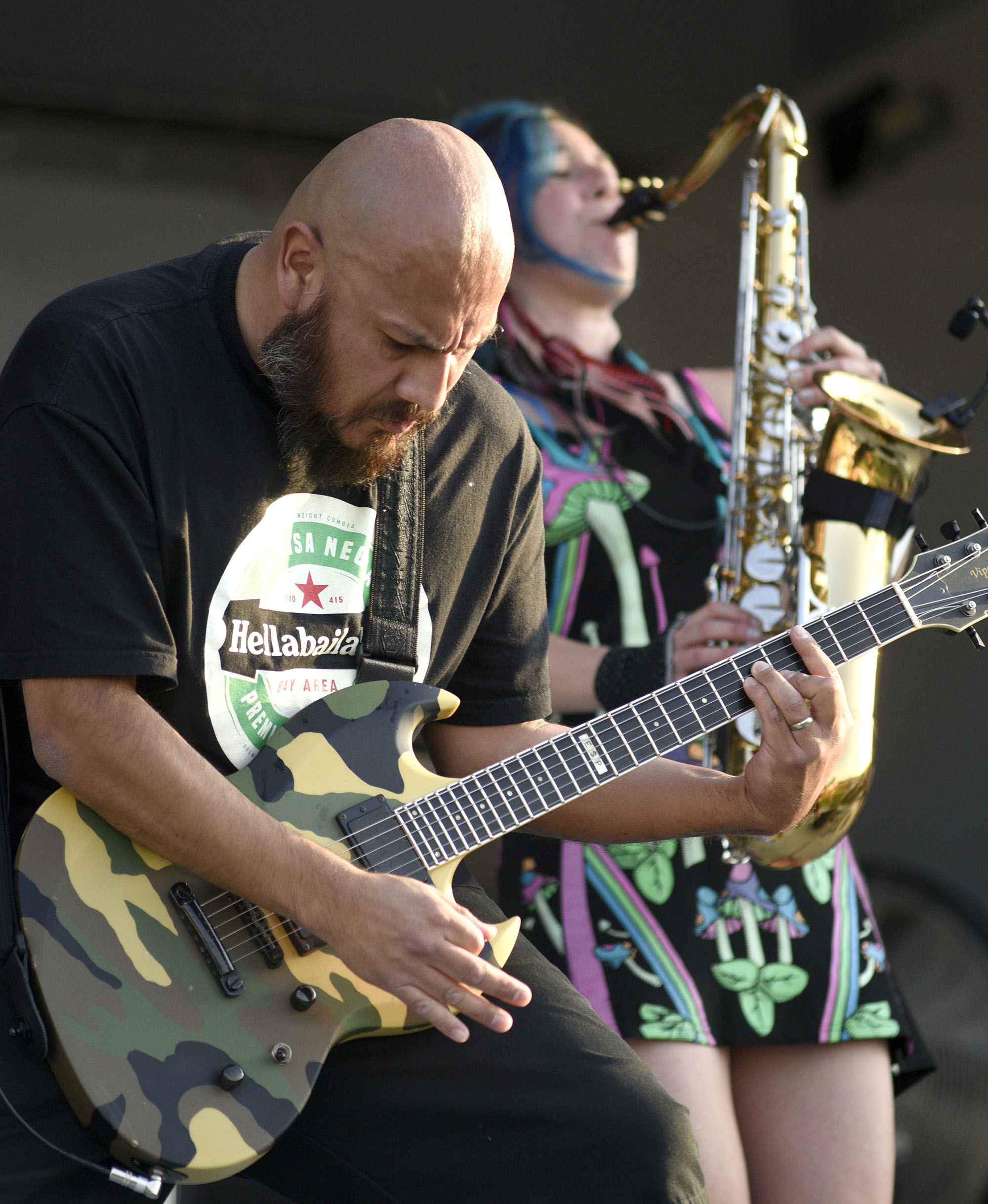 Marco Polo Santiago, with the band La Misa Negra, plays guitar while Morgan Nilsen plays the saxophone in the background on the Chevy Stage.