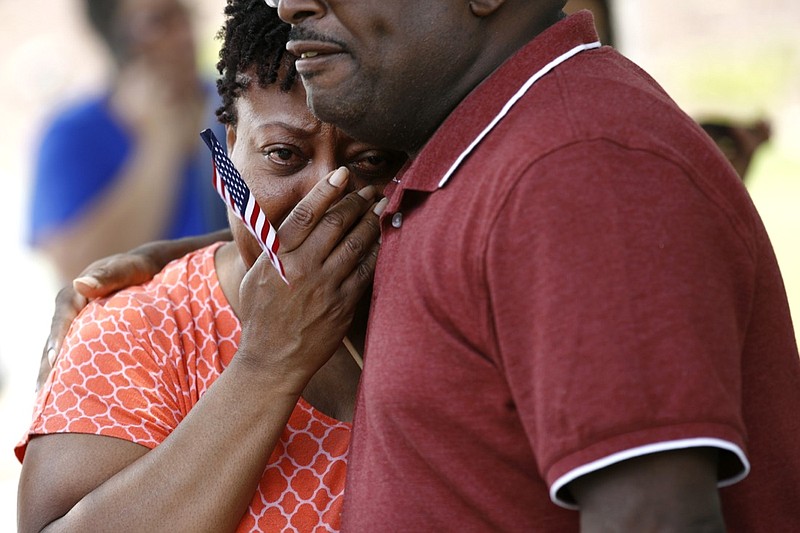 Patricia Olds, a coworker of LaQuita Brown, a victim of a mass shooting at a municipal building in Virginia Beach, Va., is comforted before carrying a cross bearing Brown's name to a nearby makeshift memorial, Sunday, June 2, 2019. (AP Photo/Patrick Semansky)