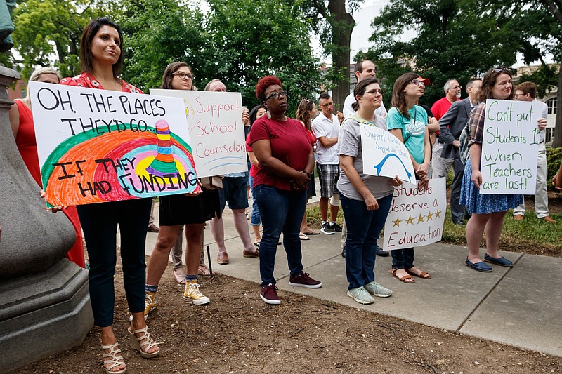Demonstrators with UnifiEd hold signs as they watch a news conference outside the Hamilton County Courthouse in support of Hamilton County Mayor Jim Coppinger's fiscal year 2020 budget on Wednesday, June 5, 2019, in Chattanooga, Tenn. Mayor Coppinger later presented his budget, which calls for a tax increase for additional funding for schools, to the county commission.
