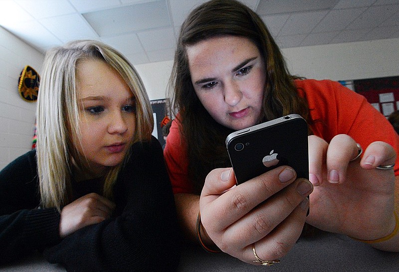 FILE - In this March 13, 2014, file photo, Hartselle High School students Lissa Blagburn and Brantlee Wright use an iPhone as they work on a networked lesson in Spanish class in Hartselle, Ala. Teachers say they're seeing so much student anxiety that a national union newsletter labels it a "mental health tsunami." Many of those educators, along with doctors and researchers, say smartphones, especially the nonstop pull of social media, are at least partly to blame. Schools are starting to react. (Gary Cosby Jr./The Decatur Daily via AP, File)

