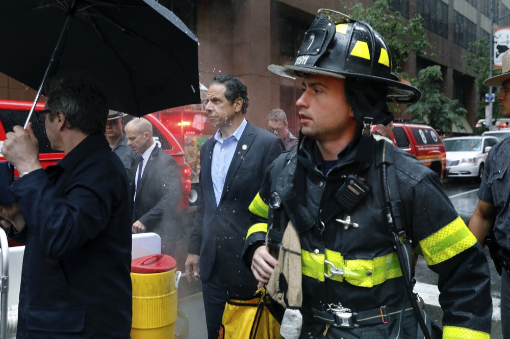 New York Gov. Andrew Cuomo and first responder personnel walk through the scene near 52st. Street and 7th Ave., Monday, June 10, 2019, in New York, where a helicopter was reported to have crash landed on top of a building in midtown Manhattan. The FDNY said at around 2 p.m. Monday that it had no further details of the incident, roughly located around 51st Street and Seventh Avenue. (AP Photo/Mark Lennihan)