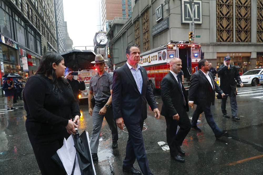 New York Gov. Andrew Cuomo, center, walks through the scene near 52nd Street and 7th Ave., Monday, June 10, 2019, in New York, where a helicopter was reported to have crash landed on top of a building in midtown Manhattan. The New York City Fire Department says the pilot of the helicopter on the skyscraper rooftop has died. (AP Photo/Mark Lennihan)
