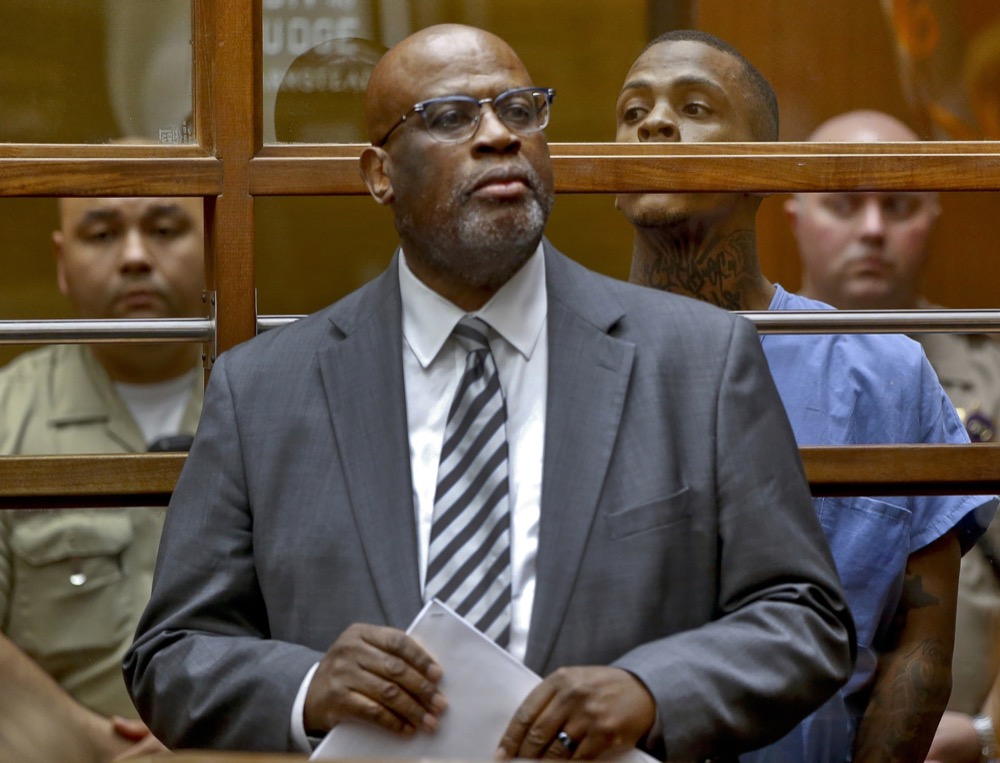 FILE - In this April 4, 2019 file photo, defense attorney Christopher Darden stands with Eric Holder, the suspect in the killing of rapper Nipsey Hussle, in a Los Angeles arraignment court. Darden, the co-prosecutor in the O.J. Simpson murder trial in 1995, is now a defense attorney himself. He recently represented the man charged with killing hip-hop mogul Nipsey Hussle before withdrawing from the case, saying his family had received death threats. Darden has also taught law, appeared on television as a legal commentator and wrote of his Simpson trial experiences in the book, “In Contempt.” (AP Photo/Damian Dovarganes, Pool, File)