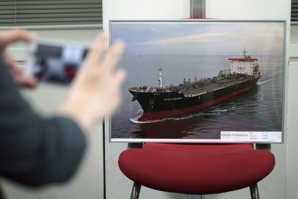 A journalist photographs a pictures of the Kokuka Courageous, which was attacked near the Strait of Hormuz, at Kikuka Sankyo Co., LTD, owner of the Kokuka Courageous, Thursday, June 13, 2019, in Tokyo. (AP Photo/Eugene Hoshiko)