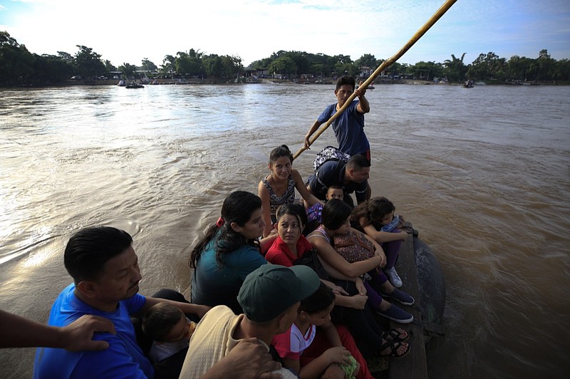 A group of more than a dozen Honduran migrants ride a raft across the Suchiate river after between Tecun Uman, Guatemala, top, and Ciudad Hidalgo, Mexico, Friday, June 14, 2019. Raftsmen and riverfront business operators said the flow of migrants through the crossing has slowed since the announcement a few days ago that Mexico's new National Guard would be deploying to the border. (AP Photo/Rebecca Blackwell)