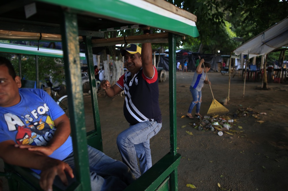 Bike taxi drivers and business owners wait for the arrival of local commuters and migrants by raft, along the Suchiate riverfront in Ciudad Hidalgo, Mexico, Friday, June 14, 2019. Raftsmen and riverfront business operators said the flow of migrants through the crossing has decreased noticeably since the announcement a few days ago that Mexico's new National Guard would be deploying to the border. (AP Photo/Rebecca Blackwell)