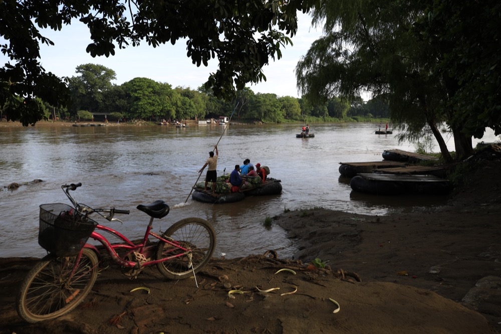 Passengers and bags of produce leave by raft from Tecun Uman, Guatemala toward Ciudad Hidalgo, Mexico, top, on Friday, June 14, 2019. Raftsmen and riverfront business operators said the flow of migrants through the crossing has decreased noticeably since the announcement a few days ago that Mexico's new National Guard would be deploying to the border. (AP Photo/Rebecca Blackwell)