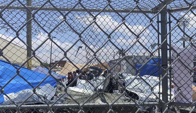 In this June 1, 2019, photo, provided by New Mexico State University professor Neal Rosendorf, migrants are seen through fencing inside a temporary outdoor encampment where they re waiting to be processed in El Paso, Texas. Rosendorf said it resembled a human dog pound. (Neal Rosendorf via AP)


