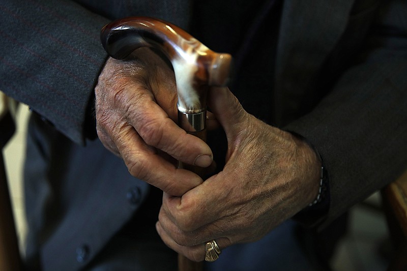 An elderly man holds his walking stick in May.