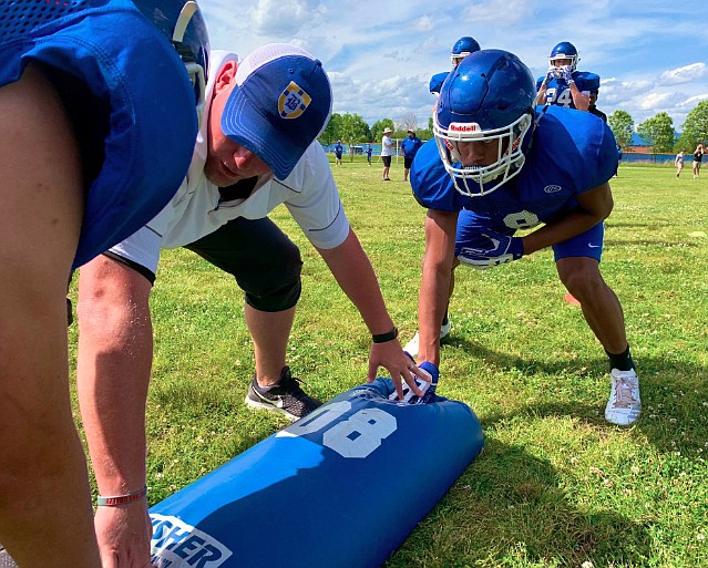 First-year Boyd Buchanan football coach Jeremy Bosken works on a blocking drill with Buccaneers players.