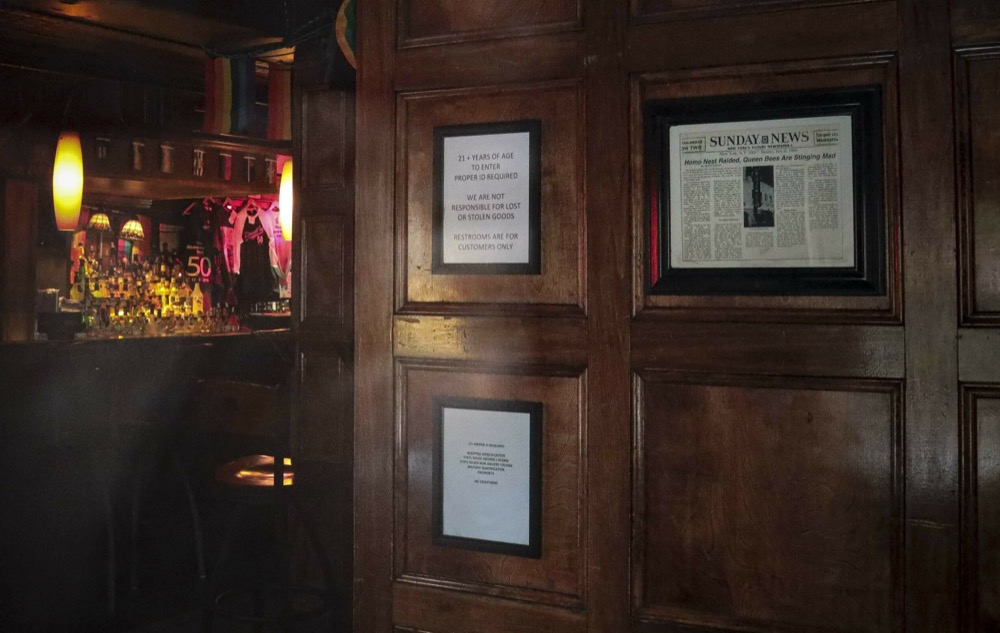 In this Friday, June 14, 2019, photo, a framed newspaper clipping, right, hangs near the entrance of the Stonewall Inn in New York, headlining the 1969 riots that followed a police raid of the bar. Some of the coverage of rioting was itself a source of the fury that led Stonewall to become a synonym for the fight for gay rights.(AP Photo/Bebeto Matthews)
