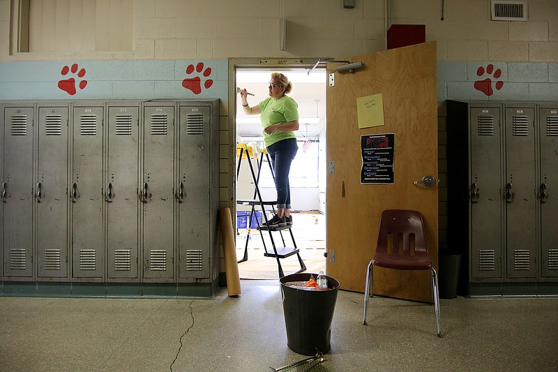 Mary Penagos, a mortgage loan officer at Regions, paints around a door frame at Brainerd High School Tuesday, June 18, 2019 in Chattanooga, Tennessee. There were 34 organizations that took part in the revamping project at Brainerd.
