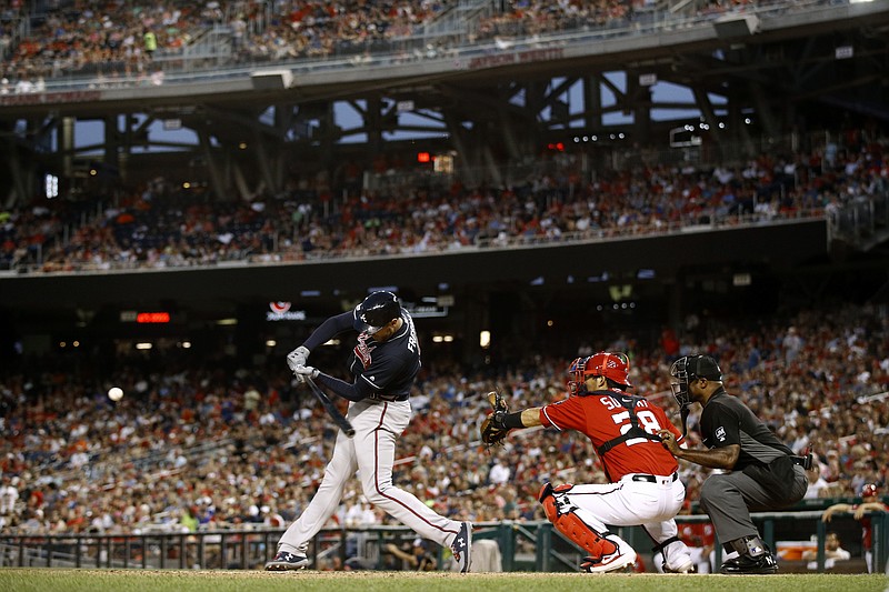 The Atlanta Braves' Freddie Freeman singles in front of Washington Nationals catcher Kurt Suzuki and umpire Alan Porter in the fifth inning of Saturday night's game in Washington. Ronald Acuna Jr. and Dansby Swanson scored on the play.