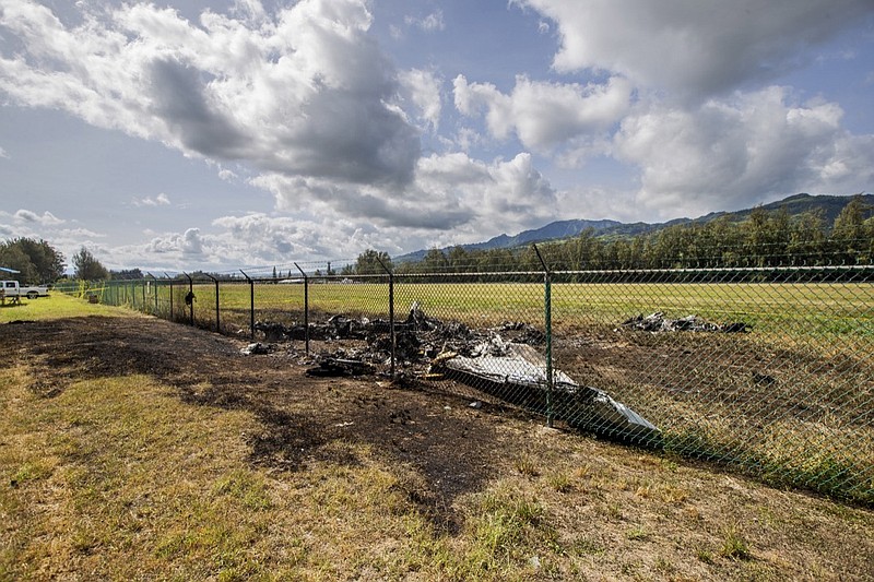 This is the site where a Beechcraft King Air twin-engine plane crashed Friday evening killing multiple people seen on Saturday, June 22, 2019, in Mokuleia, Hawaii. No one aboard survived the skydiving plane crash, which left a small pile of smoky wreckage near the chain link fence surrounding Dillingham Airfield, a one-runway seaside airfield. (Dennis Oda/Honolulu Star-Advertiser via AP)