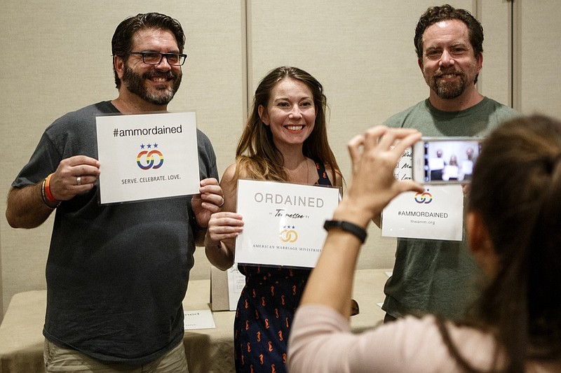 American Marriage Ministries Operations and Outreach Manager Natasha Anakotta takes a photo of Jeremy Hall, left, Laura Fitness and Chris Leach after they filled out their paperwork to get ordained at the Hampton Inn at Hamilton Place on Tuesday, June 25, 2019, in Chattanooga, Tenn. Responding to the recent Tennessee law change outlawing online ordination programs American Marriage Ministries held an ordination training.