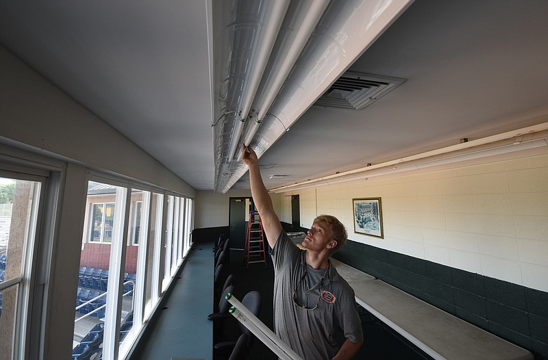 Tri-State Electrical Contractors apprentice Austin Dover removes florescent lighting in the press box area of Frost Stadium at Warner Park to install T8 LED tubes that will save the city 50-percent power usage, according to Erik Schmidt, director of sustainability for the Mayor's office.