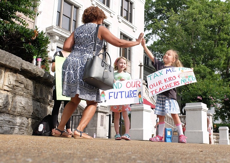 Addy Lovellette, 6, right, receives a high-five from Debbie Caudle outside the Hamilton County Courthouse Wednesday morning as hundreds crowd the fourth floor and the county commission room. Sophie Boggs, center, holds her "Future" sign. / Staff photo by Tim Barber