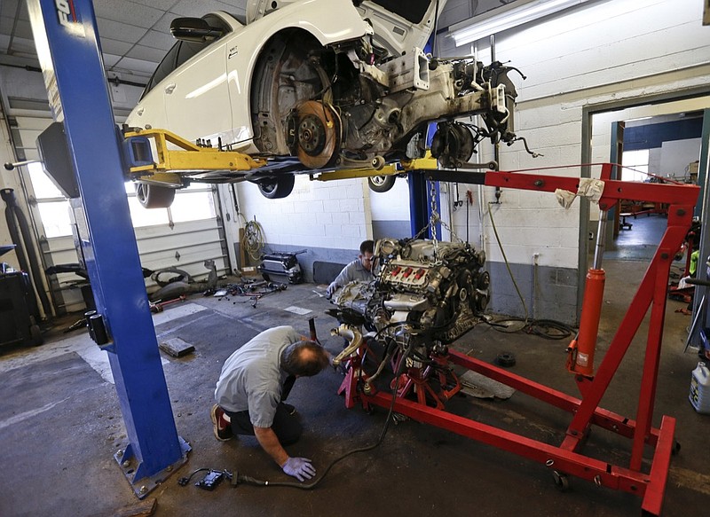FILE - In this April 26, 2018, file automotive technicians Don Dimond, left, and Bernie Rabinovitz prepare to separate an engine and transmission assembly at a repair shop in Harmony, Pa. The average age of cars and trucks in the U.S. has hit a record 11.8 years, as better quality and technology allows people to keep them on the road longer. (AP Photo/Keith Srakocic, File)
