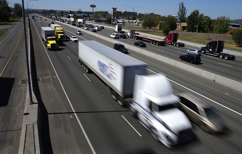 FILE - In this Wednesday, Aug. 24, 2016, file photo, truck and automobile traffic mix on Interstate 5, headed north through Fife, Wash., near the Port of Tacoma. Two U.S. senators have introduced a bill that would electronically limit tractor-trailer speeds to 65 miles per hour, a move they say would save lives on the nation's highways. Georgia Republican Johnny Isakson and Delaware Democrat Chris Coons introduced the measure Thursday, June 27, 2019.  (AP Photo/Ted S. Warren, File)