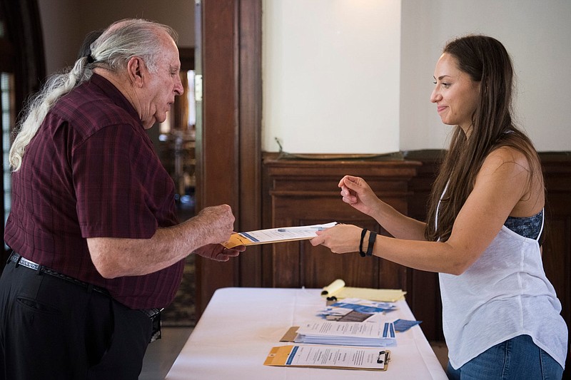 Natasha Anakotta hands paperwork to David Comer at an event held by American Marriage Ministries at Blue Slip Winery to offer in-person ordinations Wednesday, June 26, 2019. A new Tennessee law that bars online-ordained ministers from performing weddings was supposed to take effect July 1, but now it awaits a judge's decision. Chief District Judge Waverly Crenshaw scheduled a July 3 hearing in Nashville on a restraining order requested by Universal Life Church Ministries. (Caitie McMekin/News Sentinel)