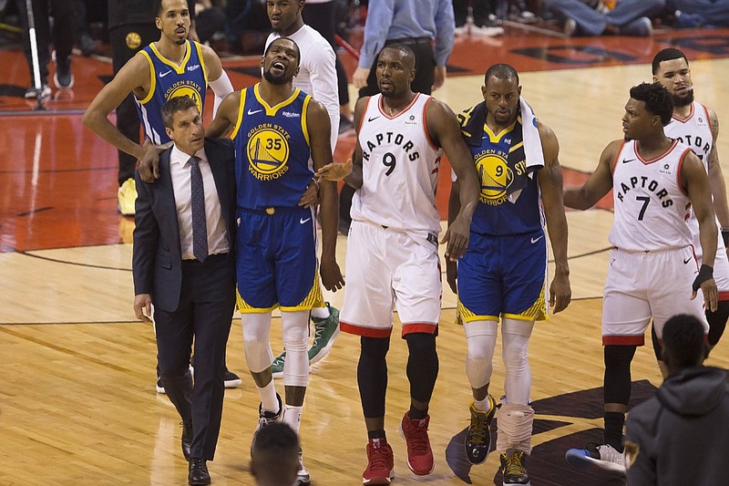 In this Monday, June 10, 2019 file photo, Golden State Warriors forward Kevin Durant (35) walks off the court after sustaining an injury as he is accompanied by Toronto Raptors center Serge Ibaka (9) and Warriors forward Andre Iguodala (9) and guard Kyle Lowry (7) during first-half basketball action in Game 5 of the NBA Finals in Toronto. On Friday, June 14, 2019, The Associated Press found that a video circulating on the internet that appeared to show fans in a Toronto bar cheering as Durant s injury is shown on a large TV screen was deceptively altered, with the Durant injury image inserted into unrelated footage of cheering soccer fans. (Chris Young/The Canadian Press via AP)