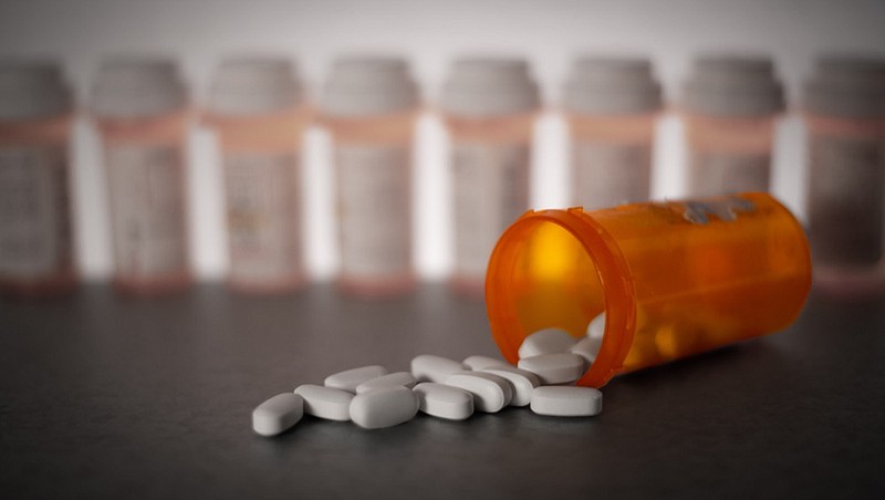 Prescription medication is strewn about, with pill bottles in the deep background. medicine tile pill tile medication tile / Getty Images