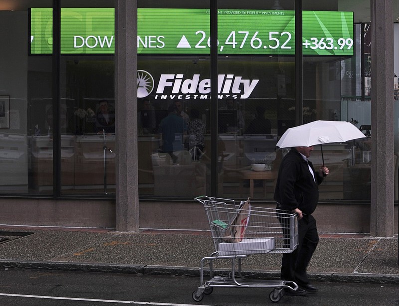 In this June 18, 2019, photo a man pulls a grocery cart as he walks in the rain past the stock ticker scroll board, showing a strong daily gain in the Dow Jones, outside Fidelity Investments in the Financial District of Boston. According to a survey by The Associated Press-NORC Center for Public Affairs Research, Americans are generally satisfied with their personal finances, but many lack confidence in their ability to afford retirement, an emergency expense or even their daily living costs (AP Photo/Charles Krupa)